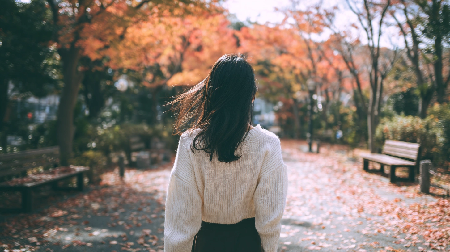 秋の公園を歩く女性
