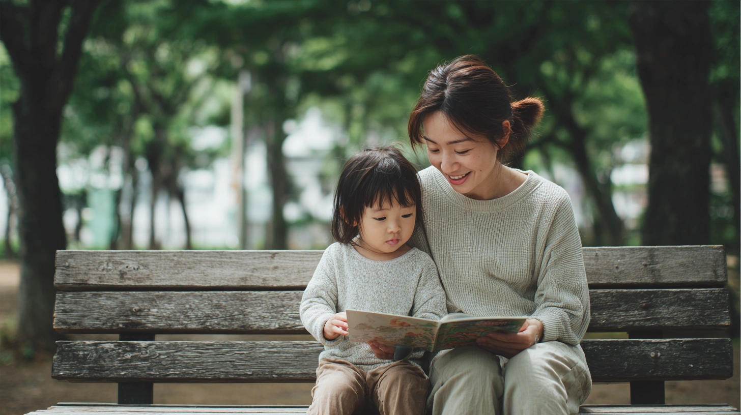 公園のベンチで絵本を読む母と子